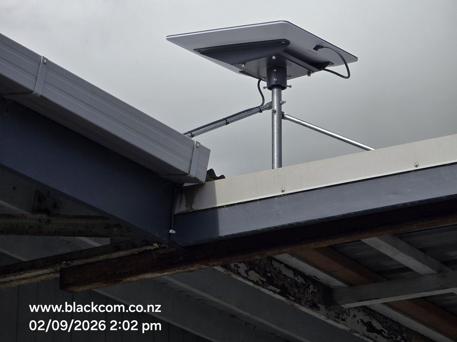 Starlink dish installed on a pole mount on a commercial roof